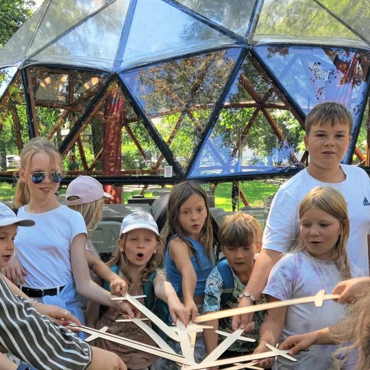 Vaikai sustoję ratu, rato viduryje surėmę medinius kardus.