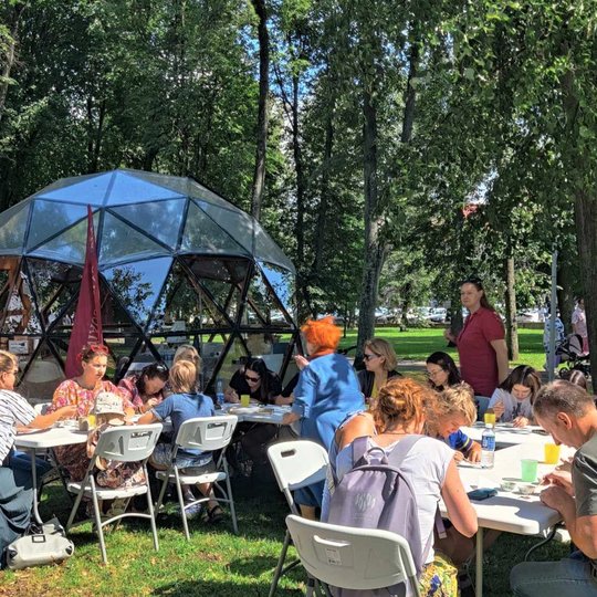 Sereikiškių parke, prie Vilniaus pilių kupolo, žmonės sėdi prie baltų stalų ir teptukais emaliuoja sau metalines figūrėles.