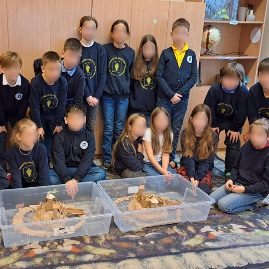 Nuotraukoje matoma devyniolikos mokinių klasę, kurios mokiniai išsirykiavę stovi už dviejų sukonstruotų pilių maketų. Iš mokinių tamsiai mėlynos uniformos su mokykline emblema galima spręsti, kad vaikai mokosi Vilniaus kunigaikščio Gedimino progimnazijoje
