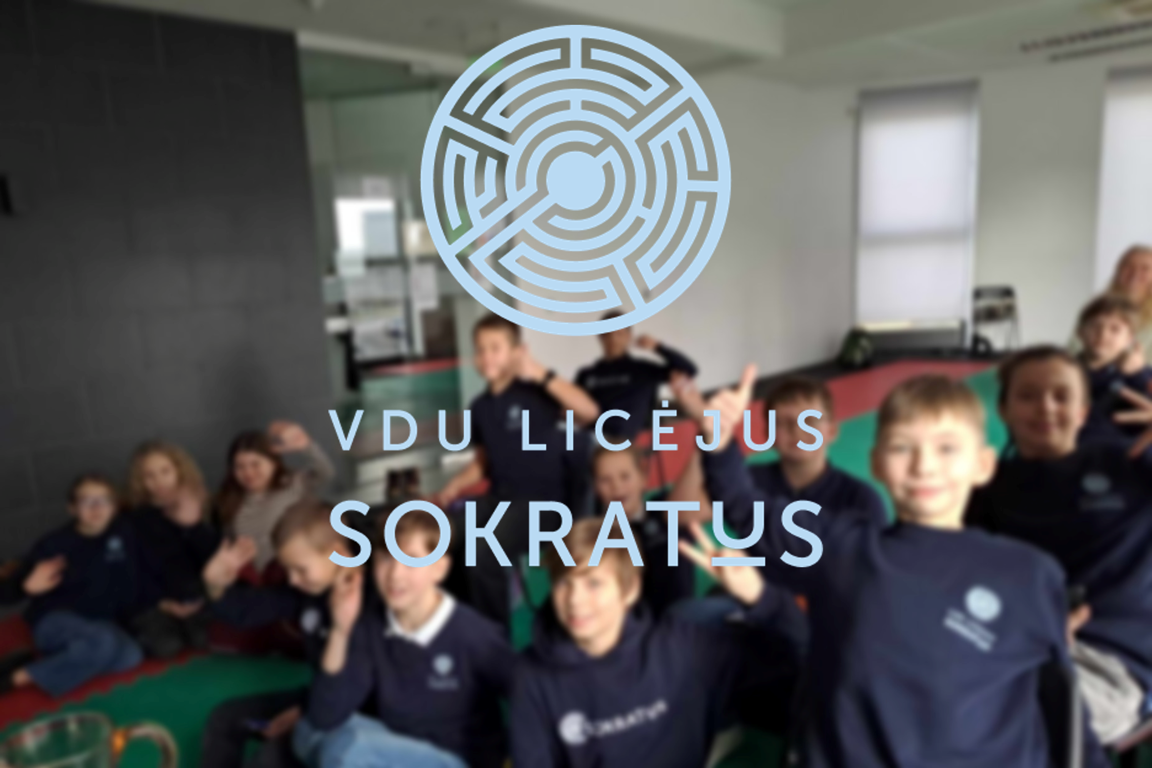 Nuotraukos centre yra pavaizduotas logotipas, kuris yra apvalios formos ir primena labirintą. Taip pat po logotipu yra parašyti   šie žodžiai "VDU LICĖJUS SOKRATUS". Fone taip matomi vaikai tačiau jie yra išblukę, nes fokusuota yra į logotipą ir pavadinim