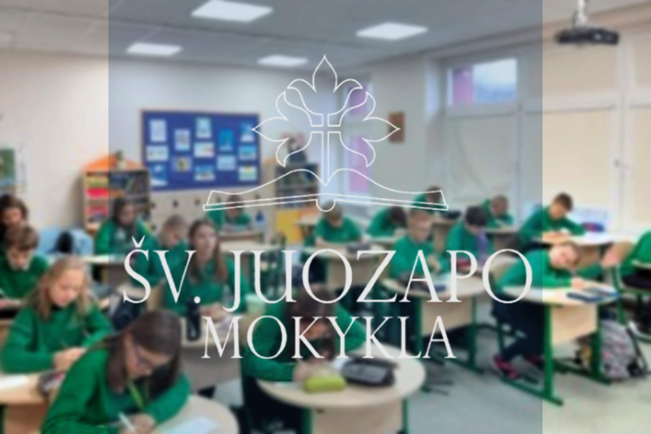 Pagrindiniame nuotraukos plane matomas mokyklos užrašas "Šv. Juozapo mokykla" ir atversta knyga su trimis tulpės žiedais kaip logotipas. Tačiau teksto matosi klasė mokinių, kurioje kiekvienas mokinys dėvi ryškiai žalią džemperį. Visi mokiniai laiko rašikl