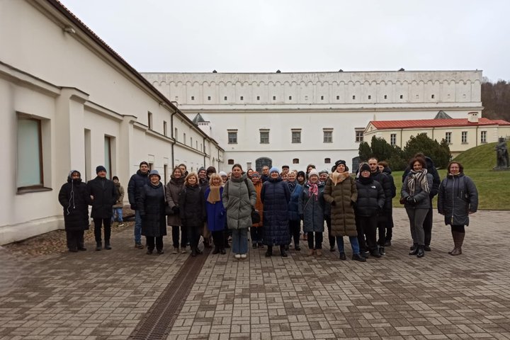 Nuotraukoje matoma grupė žmonių. Jie išsirikiavę į pakankamai tiesią liniją, tačiau daug žmonių yra ir už priekyje stovinčių žmonių. Visi jie užsidėję striukes, kai kurie dėvi kepures nuo šalčio. Nuotraukos kairėje matosi balto pastato fasadas, kuris tęsi