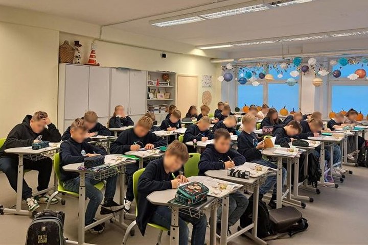 Mokiniai klasėje rašo į sąsiuvinius.