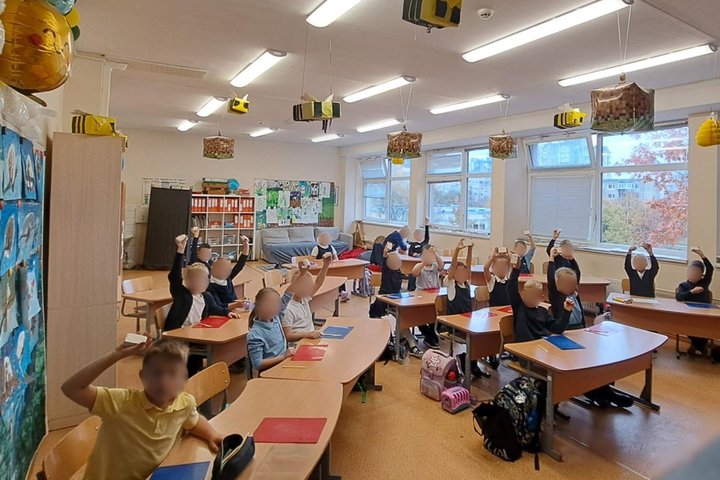 Nuotraukoje vaikai sėdi suoluose ir dalyvauja edukacijoje