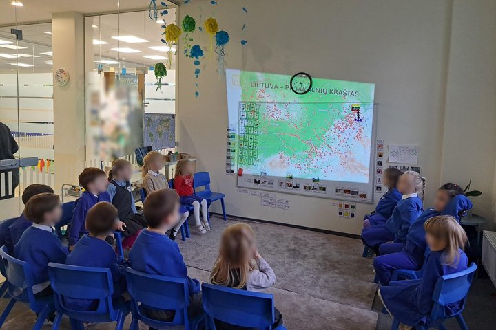 Nuotraukoje vaikai susėdę ratu, klausosi teorinės edukacijos dalies apie piliakalnius.