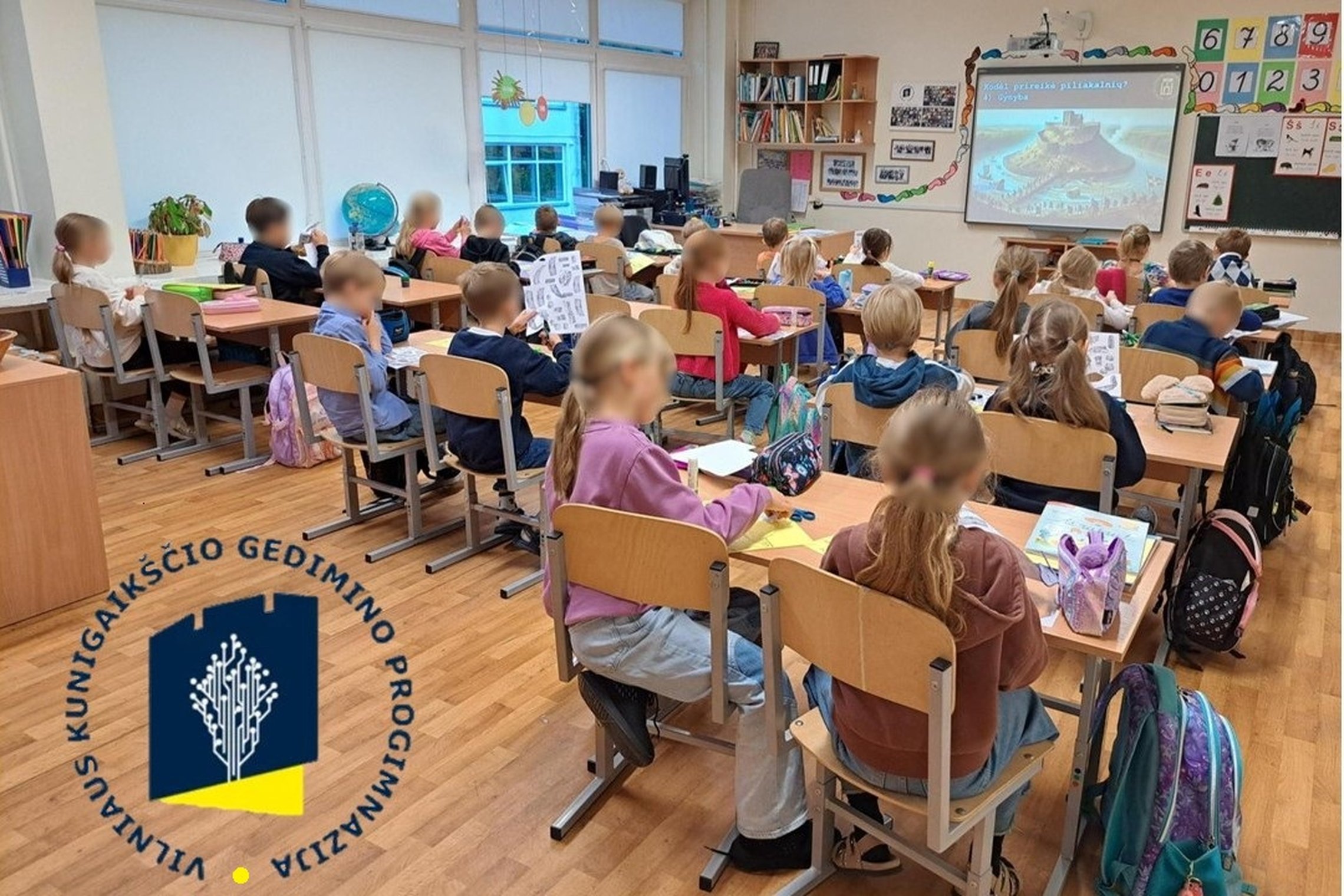 Nuotraukoje vaikai sėdi klasėje ir kuria savo piliakalnius.