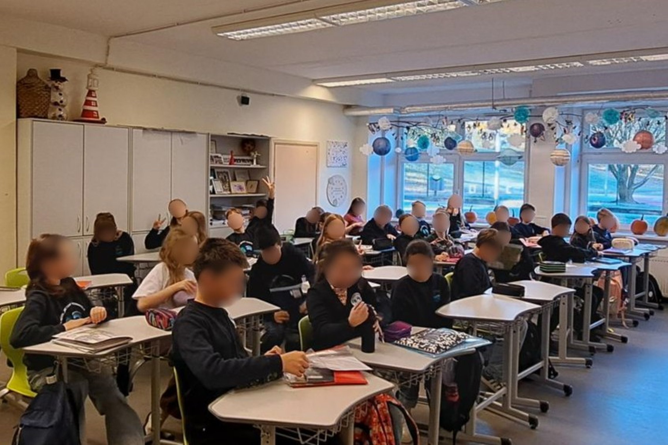 Nuotraukoje penktokai sėdi suoluose ir klausosi edukacijos.