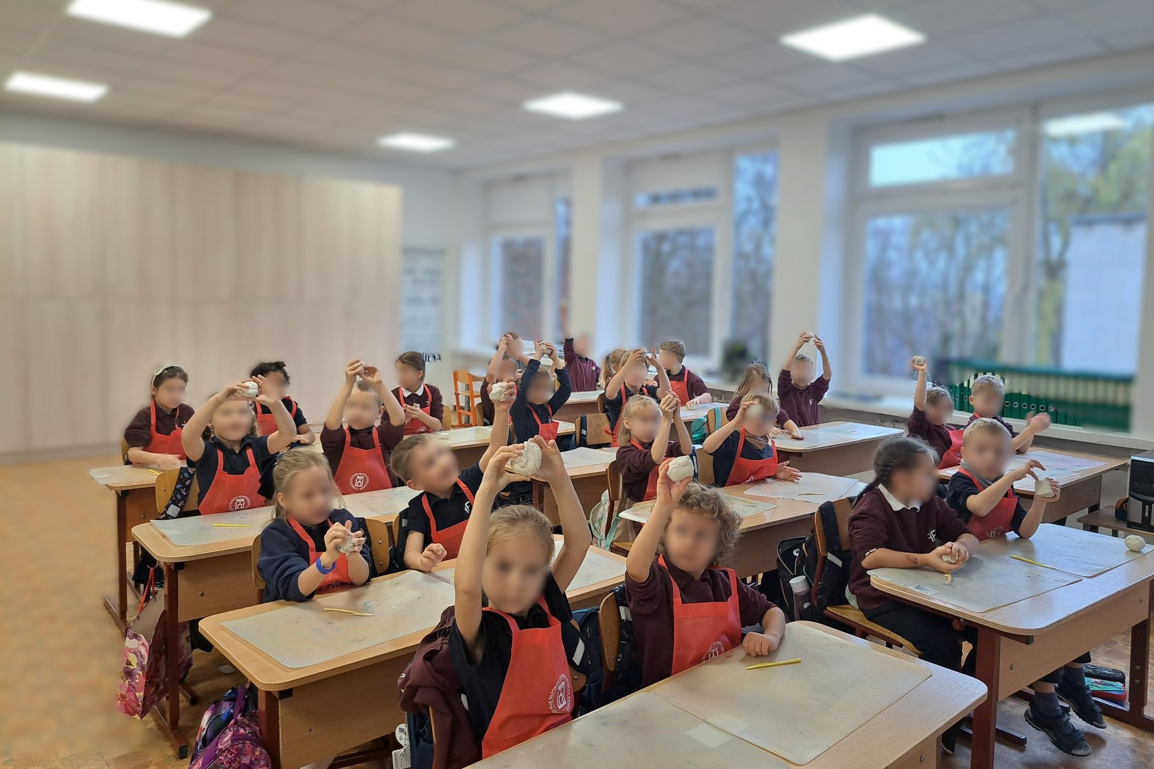 Nuotraukoje vaikai su prijuostėmis dalyvauja edukacijoje - jie lipdo bokštus iš modelino