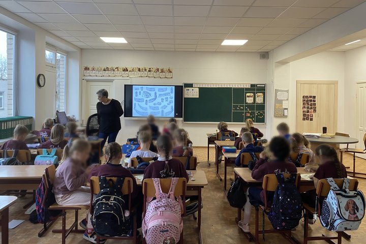Filaretų mokyklos pirmokai klasėje dalyvauja edukacijoje apie piliakalnius ir prisijaukintus gyvūnus, ekrane rodoma vaizdinė medžiaga, mokiniai dirba prie suolų.