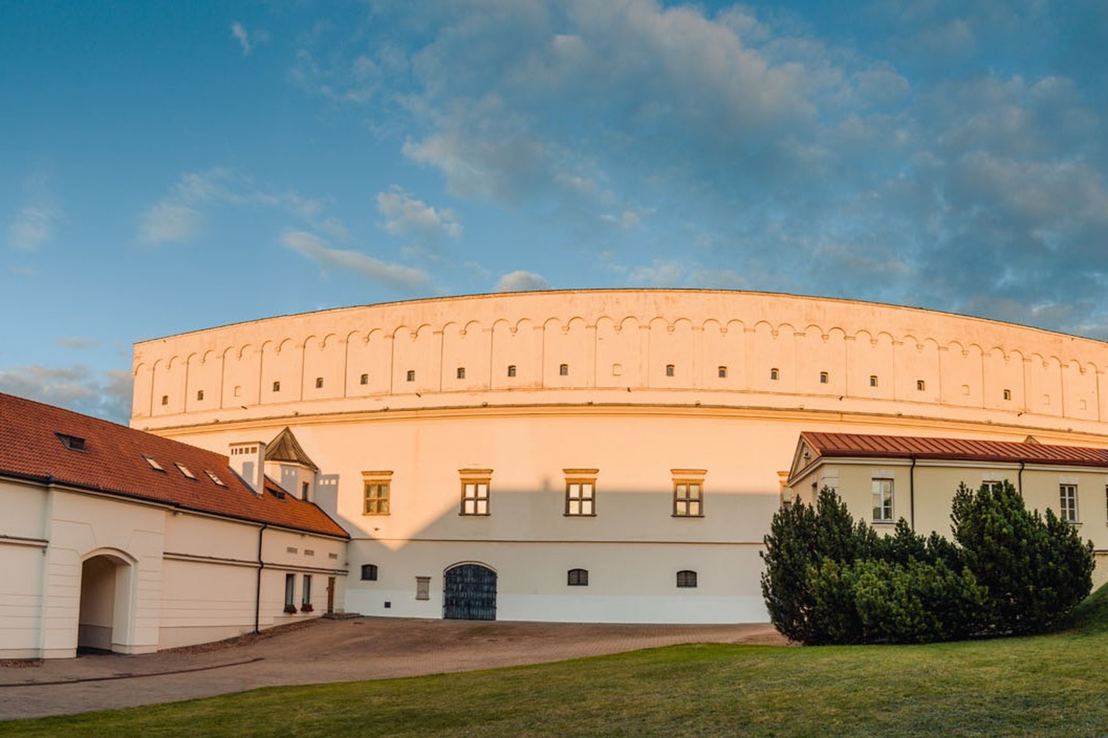 Vilniaus pilių teritorijoje esantis Senasis arsenalas – didelis pusapvalės formos istorinis pastatas su šviesiomis sienomis ir nedideliais langais. Pastatą supa kiemas ir žolė, šonuose matyti žemesni pastatai su raudonų čerpių stogais.
