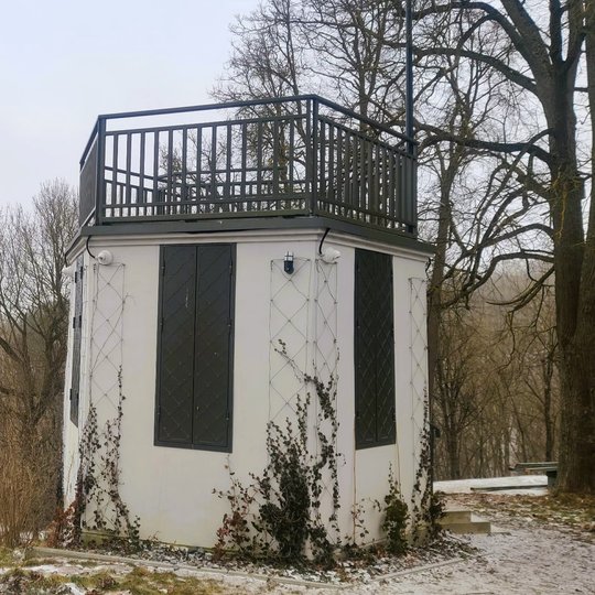 Nedidelis apžvalgos paviljonas ant kalvos su terasa viršuje. Aplink – žiemos peizažas su medžiais ir lengvu sniegu, o tolumoje matyti Gedimino kalnas su bokštu.