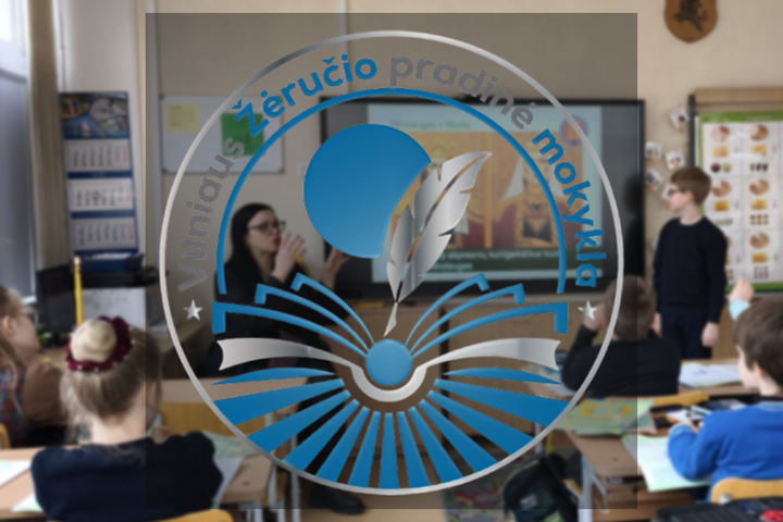 Nuotrauka yra sulieta, viduryje pavaizduotas apvalus mokyklos logotipas su užrašu "Žėručio pradinė mokykla". Nuotraukoje vaizduojama klasė, kurioje vaikai atsisukę į klasės priekį žiūri į lentą arba į savo mokytoją, kuri kažką aiškina. Pakabinta išmanioji