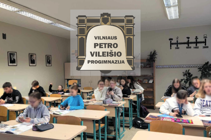 Nuotraukoje pavaizduota klasė, nufotografuota iš priekio. Suoluose vaikai sėdi po du arba po vieną, dauguma rankose laiko telefonus ir kažką žiūri. Klasės gale stovi kelios lentynos, ant šoninės sienos eilute yra pakabinti nedideli signatarų paveikslai. P