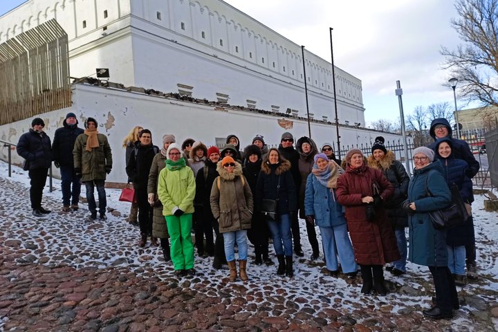 „ChatGPT“ pasakė: Nuotraukoje matoma grupė žmonių, susirinkusių priešais senovinę pastato sieną, kurios dalis yra restauruojama. Visi dalyviai vilki šiltus žiemos rūbus, kepurės ir šalikus, nes oras atrodo šaltas, matoma sniego danga. Grupė atrodo linksmi