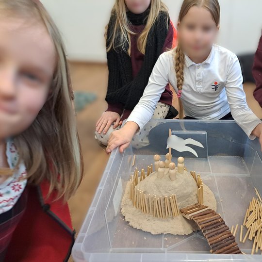Filaretų pradinės mokyklos mokinės pristato savo piliakalnio maketą – smėlio kalne pastatytą gynybinę struktūrą su kuoliukų palisada, tiltu ir balta vėliava. Edukacijos metu vaikai susipažįsta su senovės gynybos įtvirtinimais ir pilių statybos principais.