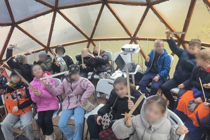 Vaikai Vilniaus pilių kupole dalyvauja edukacijoje, rankose laiko medinius kalavijus – simbolinius ginklus, kuriuos naudoja mokantis apie Lietuvos viduramžių istoriją ir riterių tradicijas.