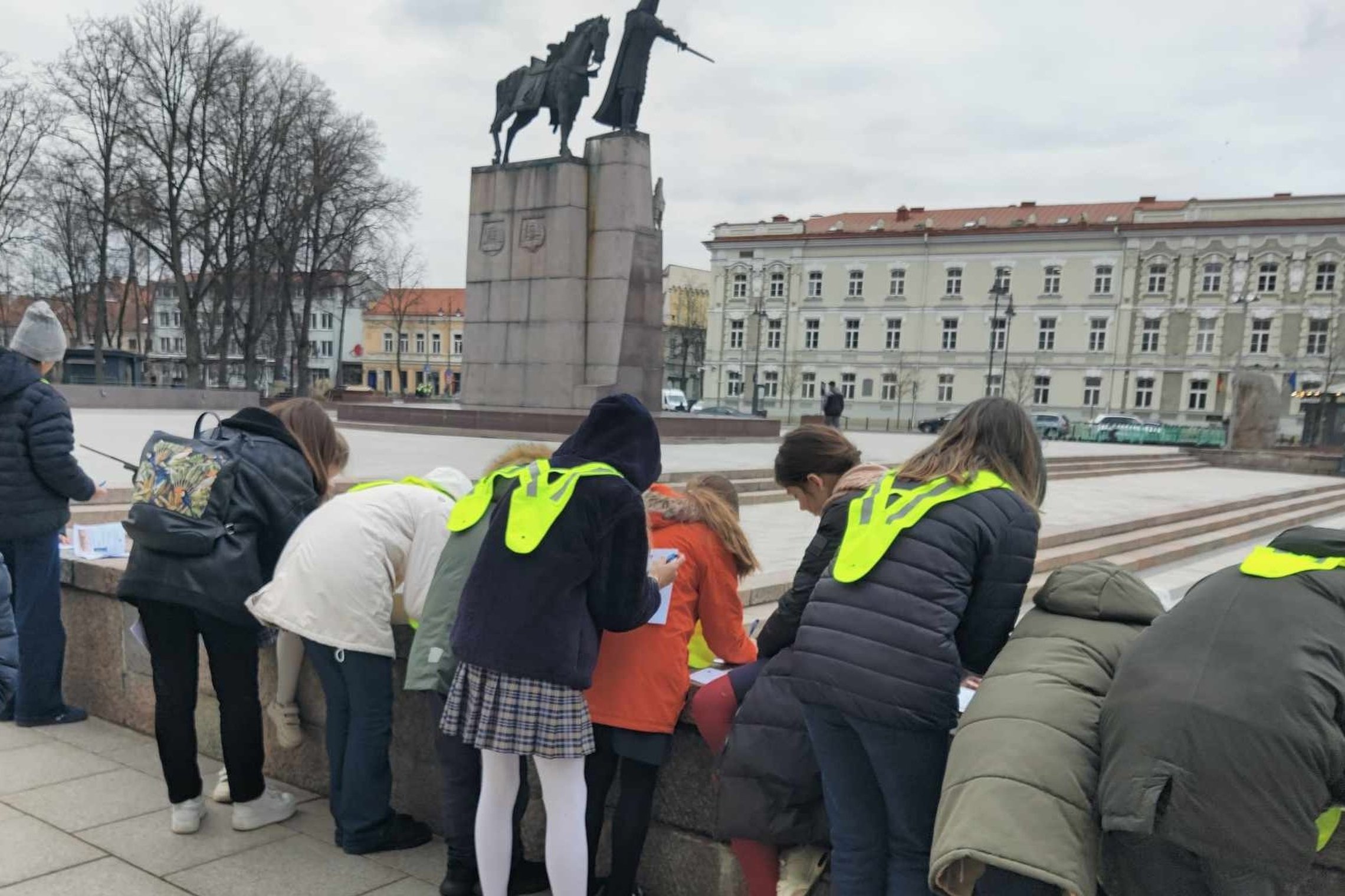 Vaikai su atšvaitais dalyvauja edukacijoje Vilniaus pilių teritorijoje, rašo užduotis prie didžiojo kunigaikščio Gedimino paminklo Katedros aikštėje.