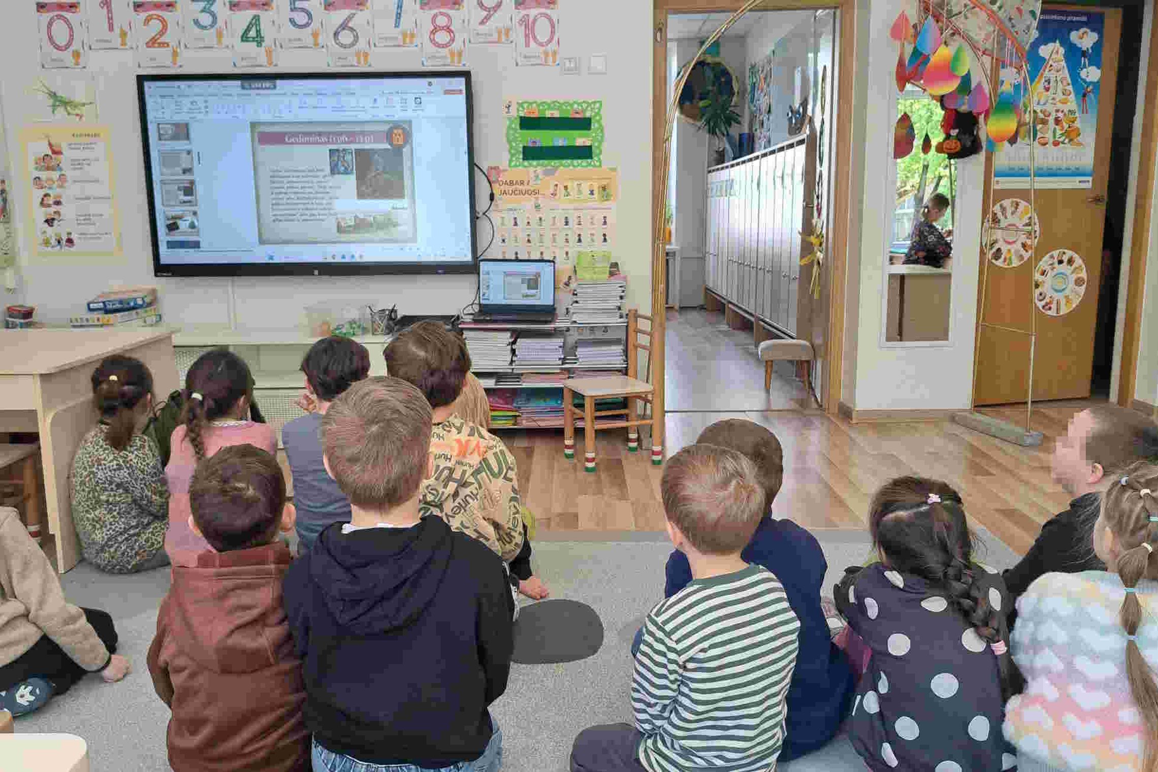 Vaikai susidomėję stebi skaidres apie kunigaikštį Gediminą ir jo sapną darželio grupėje. Priešais ekraną susėdę vaikai klausosi edukacijos apie Vilniaus įkūrimo legendą.
