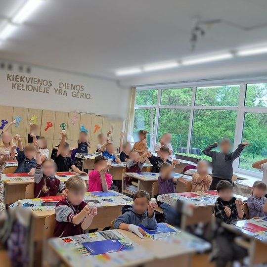 Klasė su iškeltomis molio skulptūrėlėmis Linksma, energinga atmosfera klasėje – mokiniai sėdi prie spalvingai uždengtų stalų ir išdidžiai laiko rankose savo molinius darbelius. Visi susitelkę ir kupini džiaugsmo. Užrašas ant sienos – „Kiekvienos dienos ke