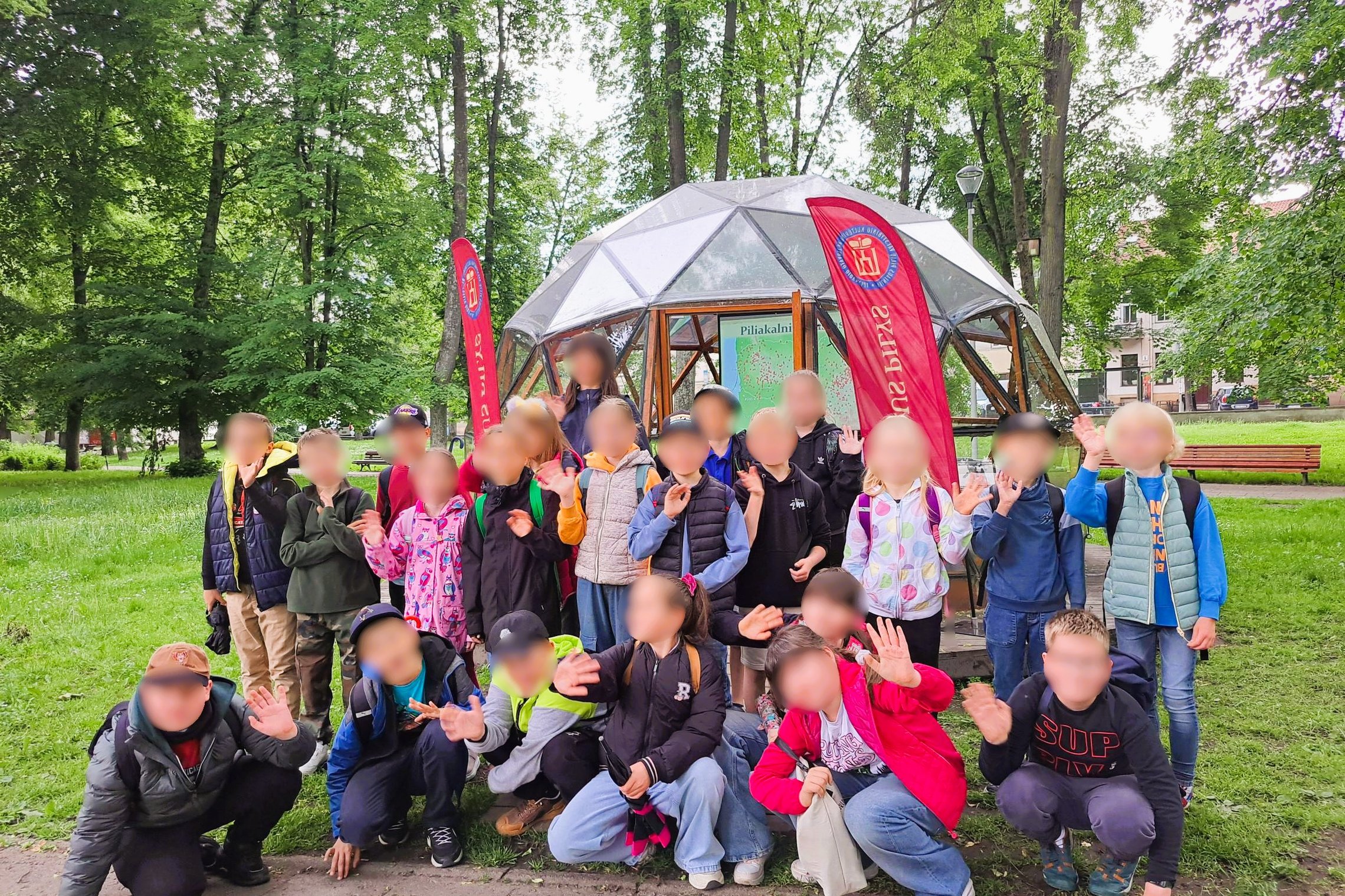 Nuotraukoje vaikų grupė pozuoja prie Vilniaus pilių kupolo, kuriame vyks edukacija apie piliakalnius.