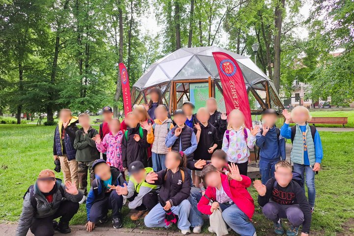 Nuotraukoje vaikų grupė pozuoja prie Vilniaus pilių kupolo, kuriame vyks edukacija apie piliakalnius.