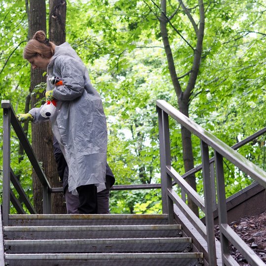 Savanorė lietingą dieną valo Gedimino kapo kalno laiptų turėklą, kuris apipieštas grafičiais bei apklijuotas įvairiais lipdukais