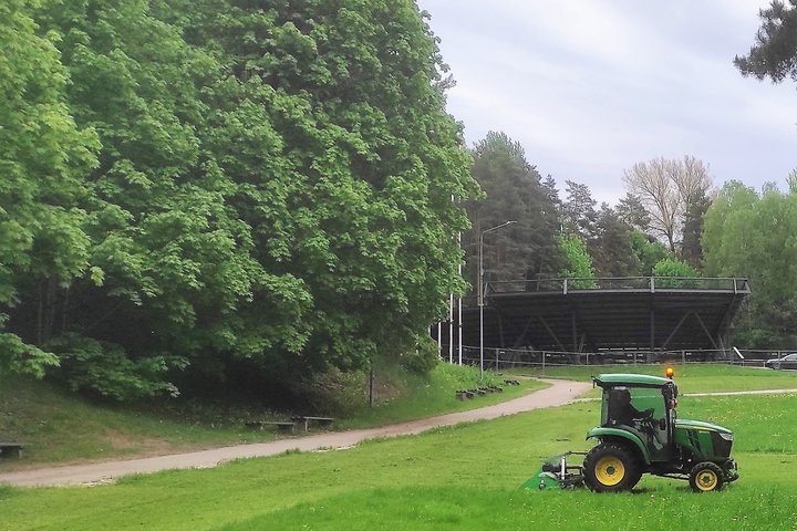 Labai šviežia vejos žolė - atliekama pirmoji pavasario šienapjūtė. Nuotraukoje žolė pjauna traktorius.