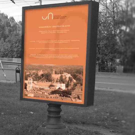 Vilniaus pilių reklaminis stendas stovi šalia gatvės, netoli Vilnios upės. Stende surašyta informacija yte su nauju rezervato ženklu.