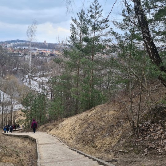 Bekešo kalno laiptai ir Vilnios upė kalno papėdėje. Laiptais leidžiasi žmonės. Vėsi pavasario diena. Dar matosi kai kur sniego ir ledo padengti plotai. Tolūmoje bažnyčių ir namų vaizdas. Ankstyvas pavasaris.