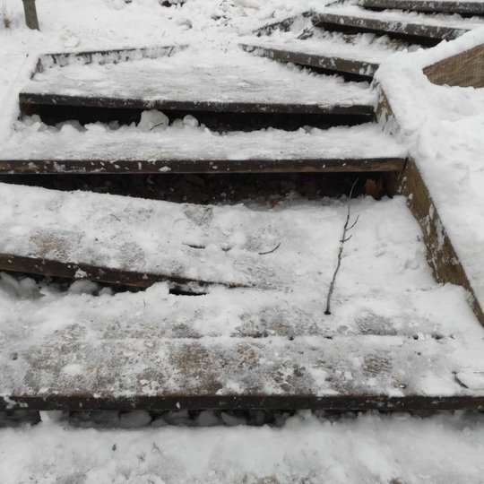 Mediniai laiptai su keliomis įlūžusiomis pakopomis. Aplink daug sniego. Laiptai nėra nauji, juos teks remontuoti.