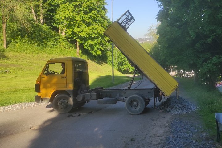 Nedidelė krovininė mašina išverčia atvežtą granitinę skaldą.