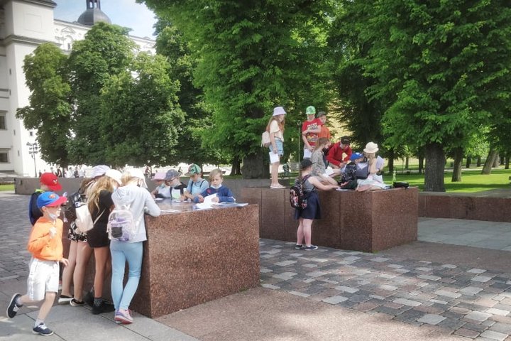 Grupė mokinių sprendžia užduotis ant granitinių blokų, kurie žymi buvusių Pilies vartų vietą.