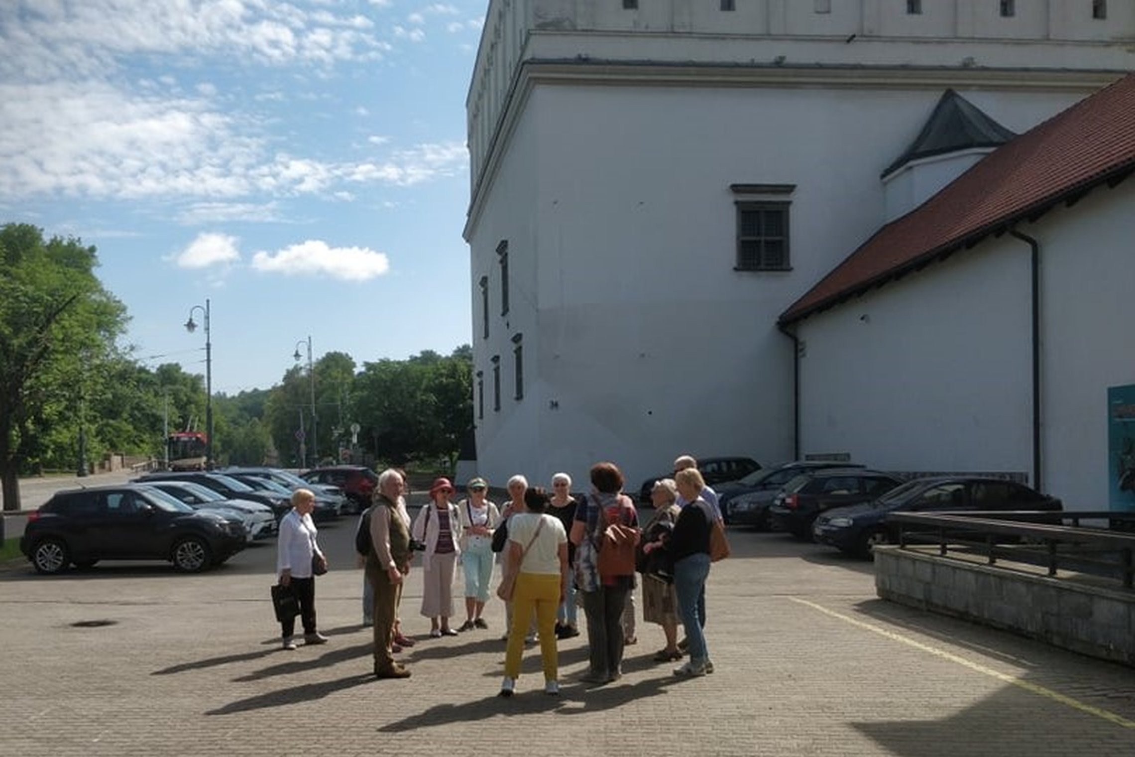 Grupė ekskursijos dalyvių būreliu sustoję prie Senojo arsenalo.