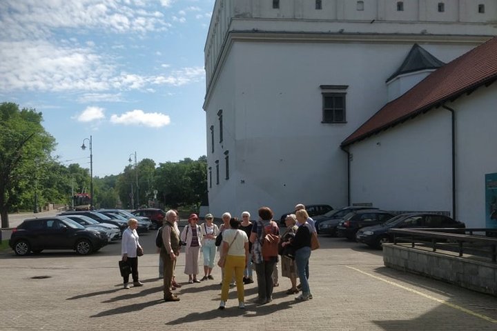 Grupė ekskursijos dalyvių būreliu sustoję prie Senojo arsenalo.