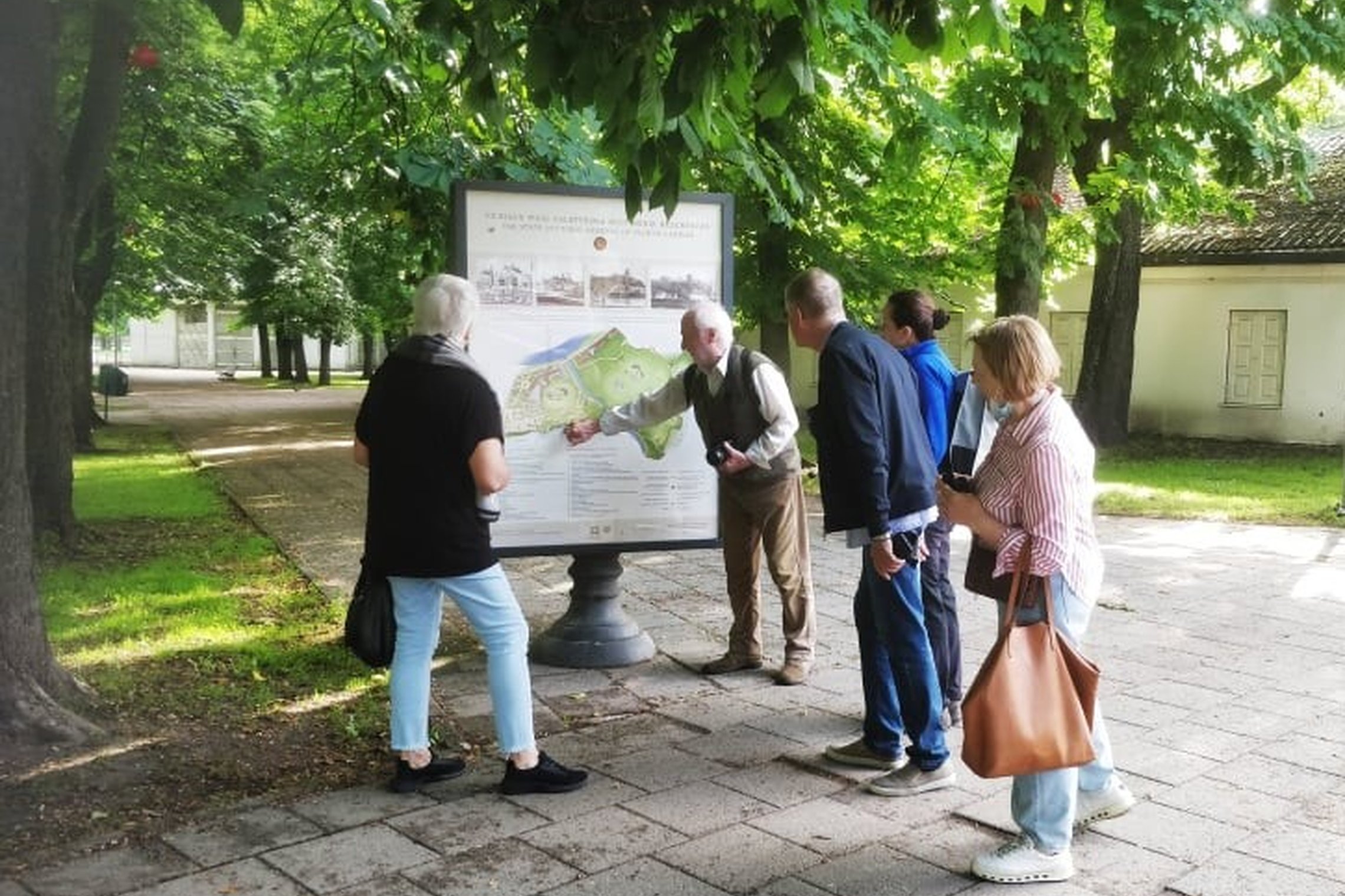 Paukščiu stebėjimo dalyviai susirinkę prie rezervato stando. Vilniaus pilių rezervato darbuotojas pasakoja ir rodo rezervato žemėlapį stende.