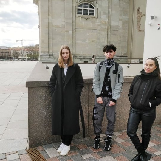 Trys studentai prie Valdovų rūmų ir Vilniaus katedros pozuoja nuotraukai.