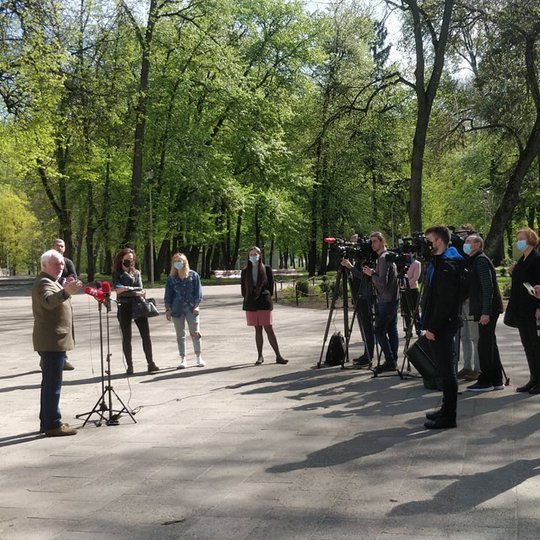 Pilių parkas, vyksta spaudos konferencija. Daug žurnalistų ir fotografų.  