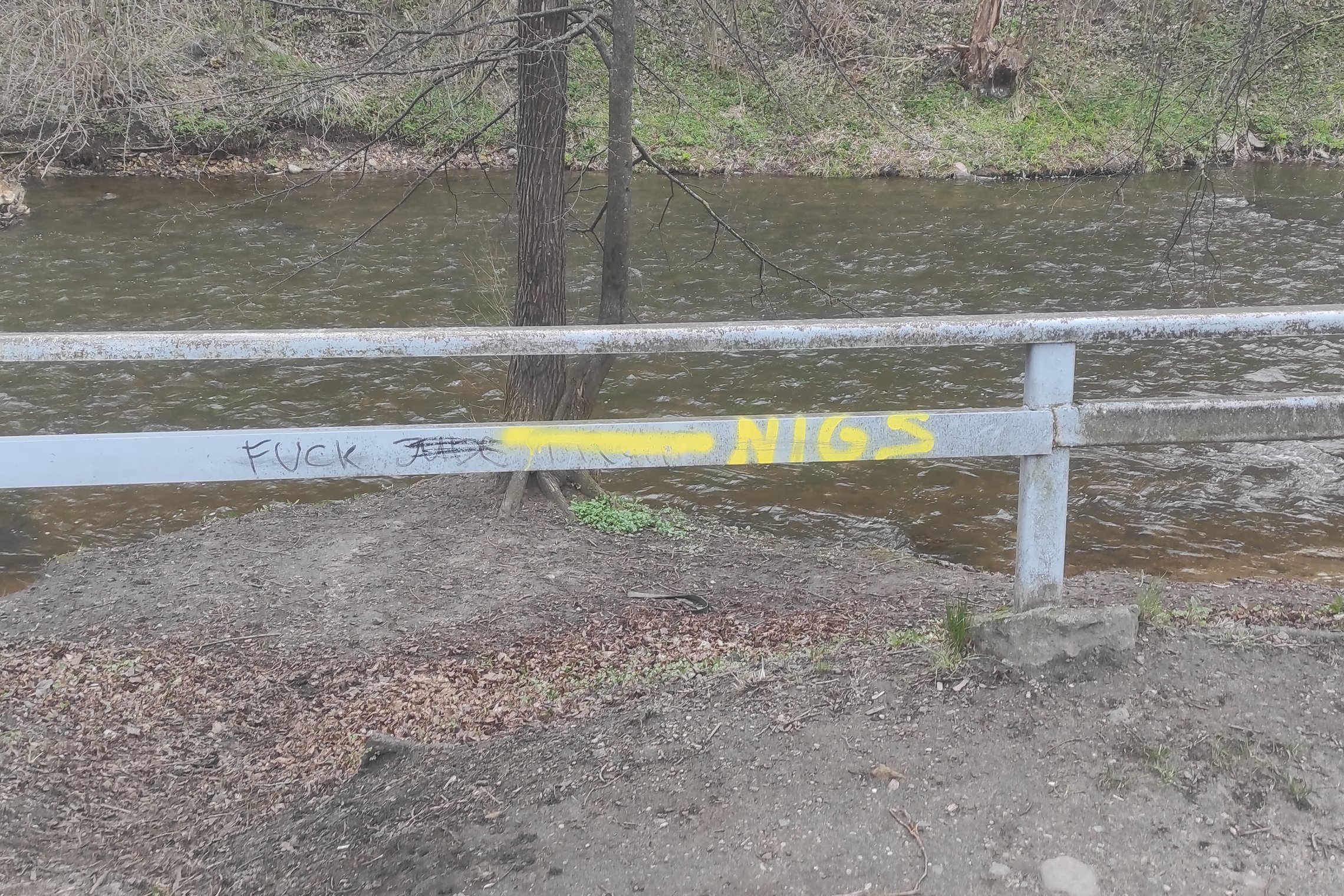 Ant Vilnios (Vinelės) kranto esantys kelio atitvarus geltonai ištepliojo graffiti „meistrai“. Už atitvaro teka upė.
