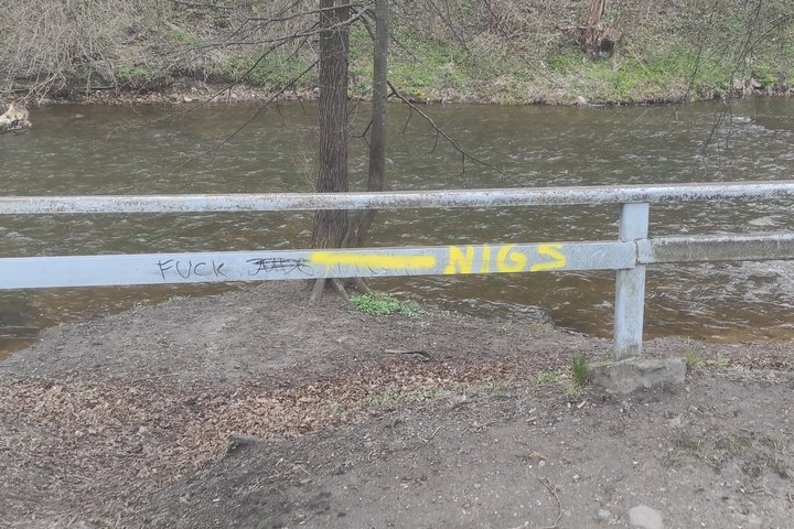 Ant Vilnios (Vinelės) kranto esantys kelio atitvarus geltonai ištepliojo graffiti „meistrai“. Už atitvaro teka upė.