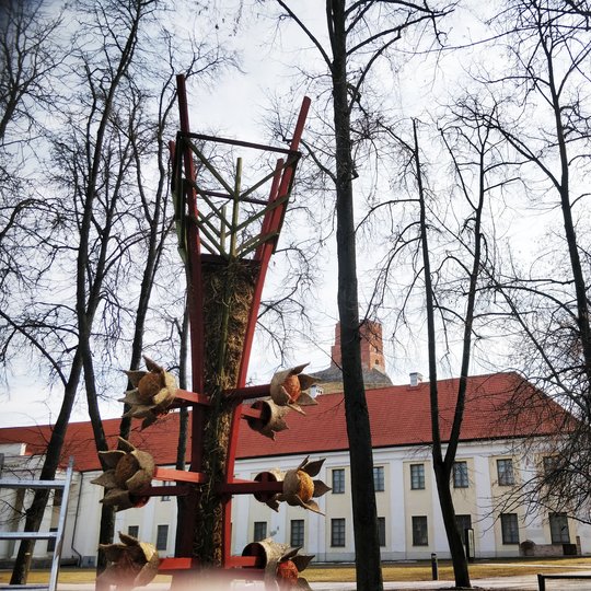 Mindaugo paminklo skvere dar neatsigavusi po žiemos veja. Ant vejos pastatyta milžiniška verba. Verbų skulptūros šiemet pasirinktos kaip Pavasario lygiadienį įprasminantis bei gyvybės medį atspindintis simbolis.