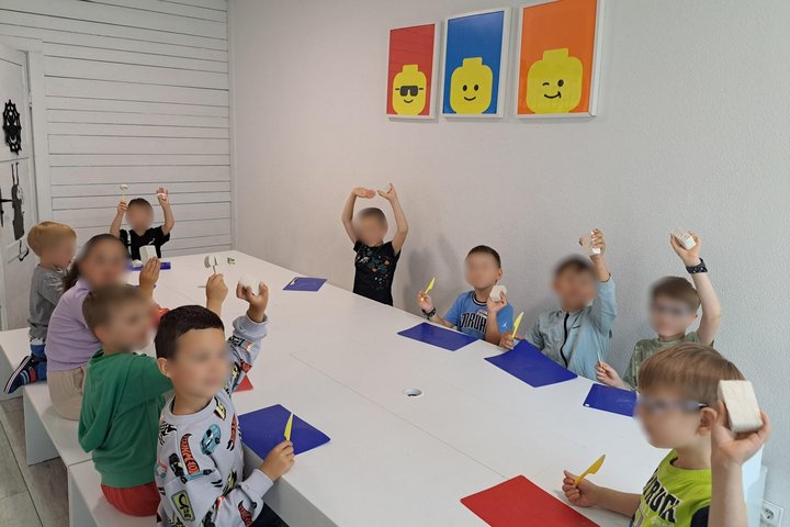Vaikai dalyvauja edukacijoje „Dinastija tavo rankose“ stovyklos patalpose, laikydami rankose įrankius ir medžiagas kūrybinei veiklai.