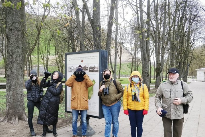 Grupė paukščių stebėtojų pasiruošę eiti į ekskursiją. Jie stovi Pilių parke prie Vilniaus pilių rezervato informacinio stendo.