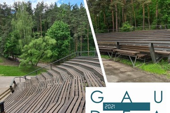 Kalnų parko Dainų slėnio naujoji medinė estrada - nuotraukos centre rudi mediniai suolai. Nuotraukos kampe - šokių šventės „Gaudeamus“ logotipas.