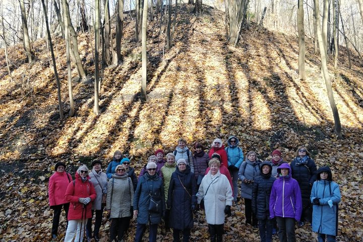 Ekskursijų dalyviai pozuoja nuotraukoje Didžiojoje griovoje. Saulėta rudens diena, lapai nuo medžių jau nukritę ant žemės.