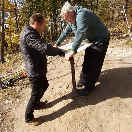Saulėta rudens diena Kalnų parke. Pėsčiųjų takas driekiasi tolyn ir dingsta pasiekęs nuokalnę. Abipus tako augantys medžiai ir krū ilgus šešėlius skersai tako apiberto geltonais ir parudusiais lapais. Nuotraukoje jų kamienai meta ilgus šešėlius skersai ta