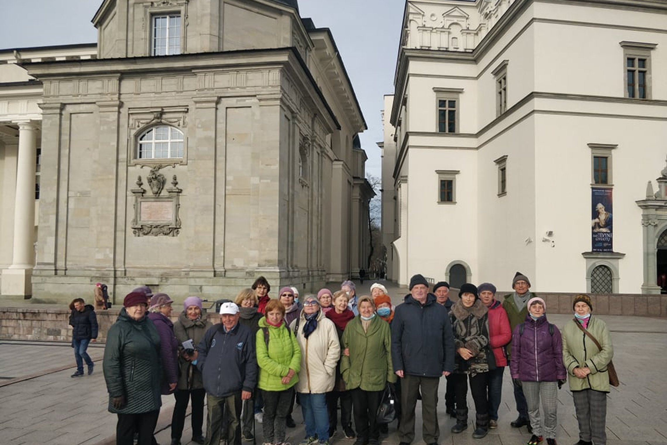 Didelė ekskursijos grupė Valdovų rūmų ir Vilniaus katedros fone. Ruduo ir žmonės šiltai apsirengę.