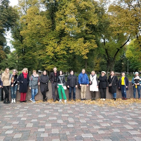 Didelė žmonių grupė išsirikiavusi pozuoja nuotraukai netoli Valdovų rūmų. U- jų nugaros matosi senas parkas su aukštais medžiais, kurie pradėjo gelsti. Į Vilnių atėjo ruduo.