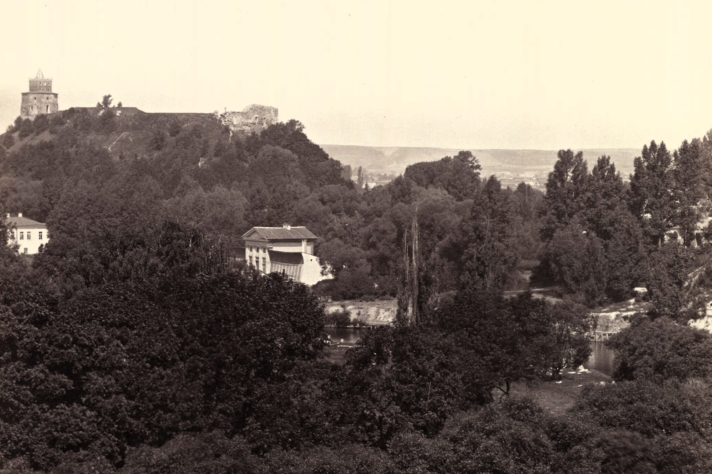 Istorinis juodai baltas Vilniaus vaizdas. Tolumoje, ant kalno, stovi Gedimino bokštas ir gretimos Vilniaus Aukštutinės pilies griuvėsiai.