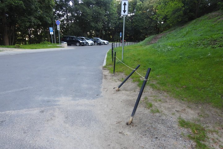 Nulenkti mediniai koliukai mašino stovėjimo aikštelėje. Vairuotojų mašinų nulenkti kuoliukai.