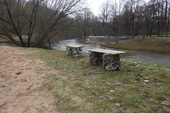 Iliustracijoje yra vaizdas, kaip atrodė du suoliukai ant Vilnios pakrantės. Tai du suoliukai su akmeninėmis kojomis ir medinėmis detalėmis.